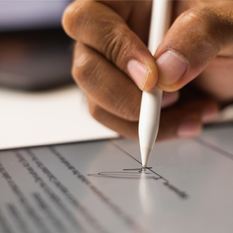 A hand signing a document with a white stylus on a tablet.
