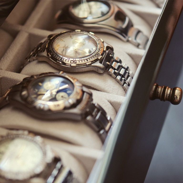 Several metal wristwatches displayed in a soft-lined storage case related to luxury watch theft